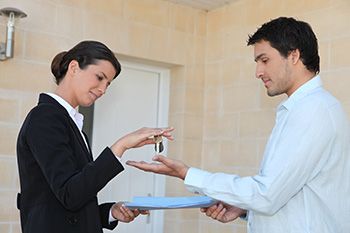 A man and a woman exchanging paperwork for a set of keys